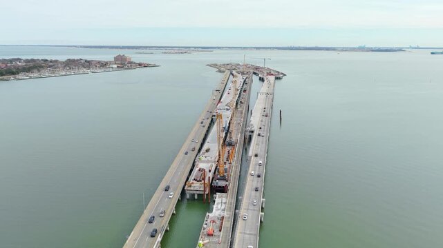 Aerial video of the Hampton Roads Bridge-Tunnel expansion project in Virginia, showing highway bridge construction, heavy cranes, and traffic over the Chesapeake Bay.