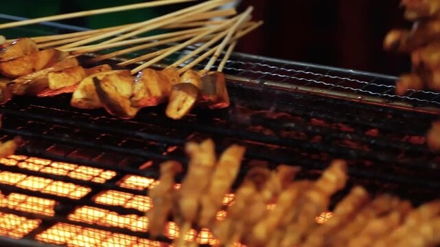 Chicken satay grilled on burning charcoal and fire. Traditional satay is street food from Indonesia. Chicken satay on traditional charcoal fire. satay on fire with smoke.