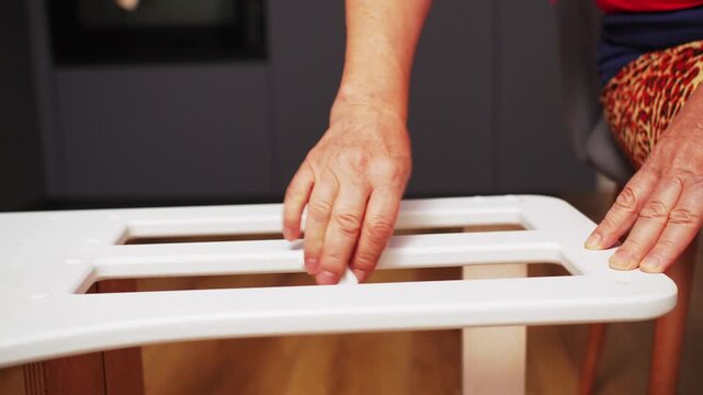 Cleaning wooden step stool in kitchen with cloth