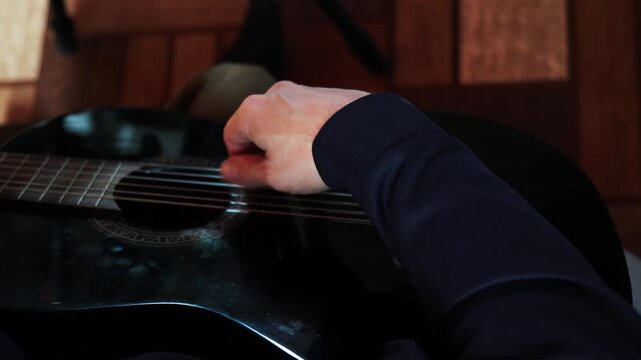 A person plays a guitar with care while sitting in a warm place. Their hands move skillfully over the strings