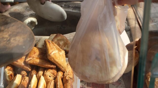 Busy trade in city bakery. Customer puts coins in baker hand and receives a bag with pastries. Selling fresh crispy baked goods in street bakery. Sale of tasty bakery and confectionery products.