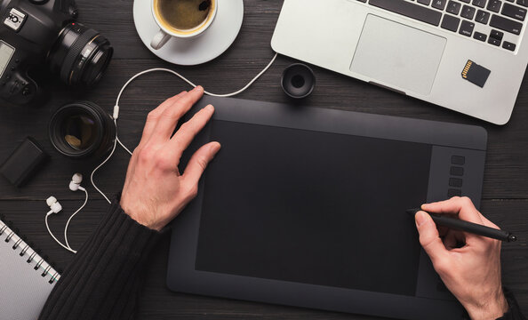 Top view on workplace of photographer. Creative designer hands working graphic tablet, photographic equipment on table