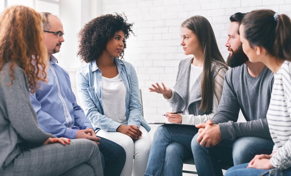 Group meeting in rehab. Diverce people talking with professional therapist, discussing their problems and progress.