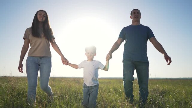 Family walking outdoors in nature. Parents holding child hand enjoying a sunny day. family time together. Parents child bonding and exploring nature. Family outdoor adventure. family outdoor nature.