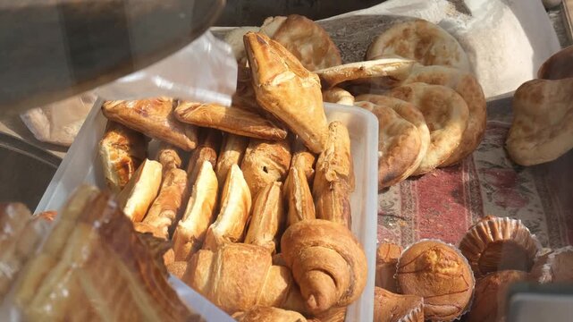 Bakery seller hands two large crispy croissants into bag for customer. Early morning breakfast purchase in street bakery with fresh aromatic bread and sweet pastries. Buying croissant for breakfast