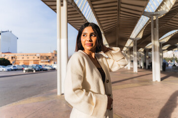 Obraz premium Young woman standing under modern architecture, looking back with natural light