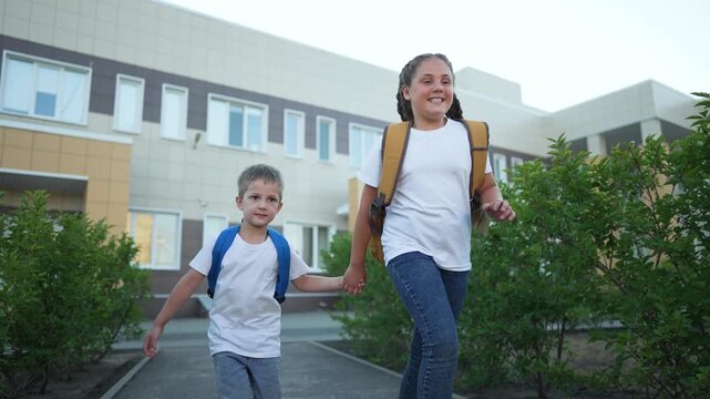 Children running to school. Siblings holding hands with backpacks. Excited children running for education. Children eager to learn. School run symbolizes education. Children school run for education.