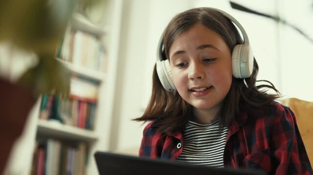  Responsible preteen girl in headphones using tablet to learn about houseplant care at home - 4k, 10bit footage.