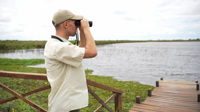 Ornithologist birdwatching at a lake with binoculars