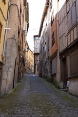 Fototapeta premium Historic narrow cobblestone alley with medieval half-timbered houses in Thiers, France