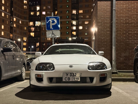 White Japanese sport car Toyota Supra IV A80 3.0 AT Turbo Sport Roof  at night the city street. Exterior of a Japanese two-door sport coupe Toyota Supra Turbo IV on parking lot. The legendary JDM car.