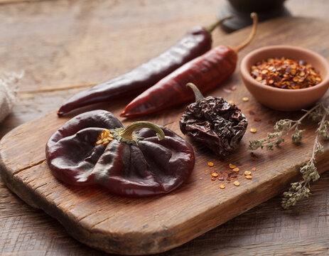 Dried chili pepper varieties, including ancho, guajillo, and chipotle, displayed on wood.