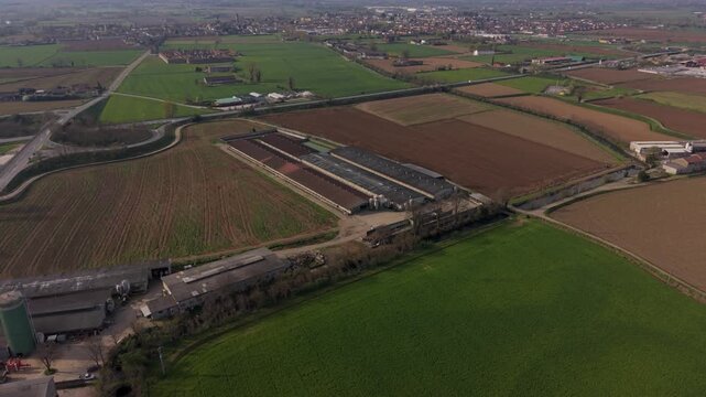 Aerial Farm Landscape: An expansive view of a modern farm, showcasing rows of agricultural buildings, cultivated fields, and winding rural roads.