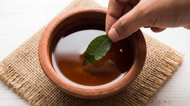 Close up of hand dipping medicinal leaf into herbal anointing oil