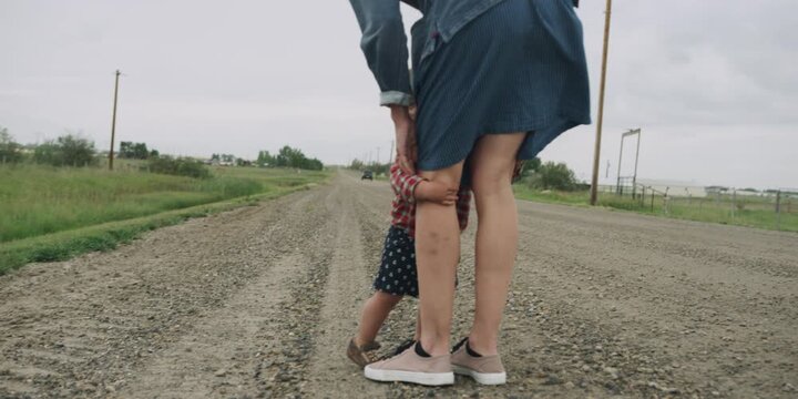 Toddler being led by the hand along a gravel road