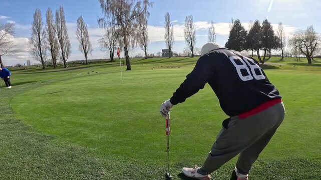 man in white toque golf putting on the green