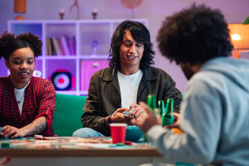 Fototapeta premium Diverse friends enjoying social card game, laughing and interacting during gathering at home