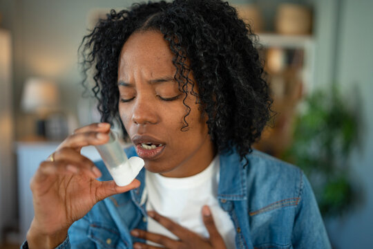 African american woman using inhaler during asthma attack