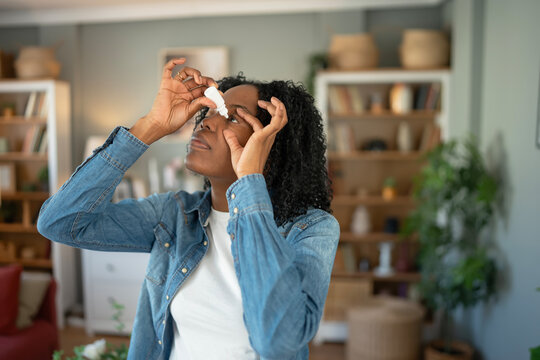 Young black woman applying eye drops for eye care