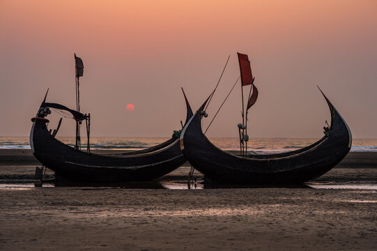 Traditional crescent-shaped moon boats on the beach at sunset.