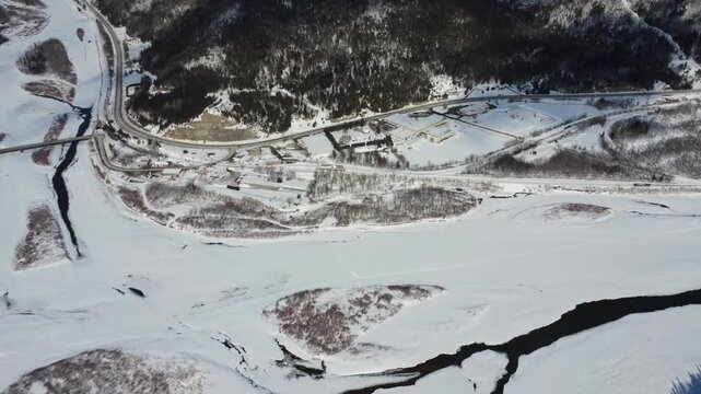 Drone view from high altitude of Matapedia, Quebec. Shows the snowy town at the junction of the Matapedia and Restigouche rivers on the Gaspe Peninsula border during a cold Canadian winter.