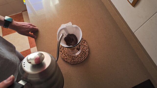 Capturing the serene process of brewing morning coffee. Hot water gently poured over fresh coffee grounds in a pour-over filter, creating a delightful daily routine.