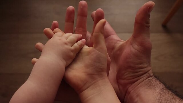 Family hands of baby, child and parents slowly releasing grip and opening palms, symbolizing freedom, growth and gentle separation while maintaining emotional connection in warm light.