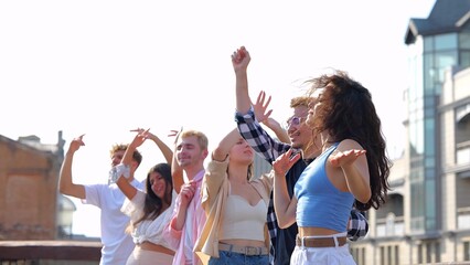 Portrait of many young Caucasian men and women dancing in positive mood and jumping to music outdoors on summer day party. Beautiful cheerful carefree people having fun at party
