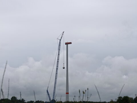 Gigantischer Schwerlastkran zieht Rotornabe f&uuml;r eine Windkraftanlage hoch, Hochbau, erneuerbare Energien, Windenergie, Aufbau eines Windrads, Energiewende
