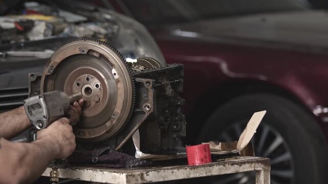 Close up of car engine flywheel installation with impact tool in auto repair workshop. Mechanical service, maintenance and engineering detail.