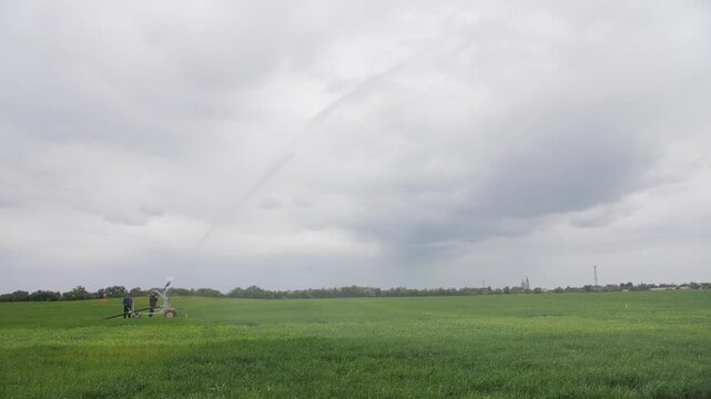 Center pivot irrigation system watering a large green crop field