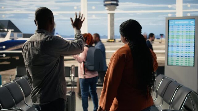 Proud parents thrilled about grown-up child independence as exchange student. Black cheerful mother and father stand in the terminal smiling and waving, embodying freedom and optimism.