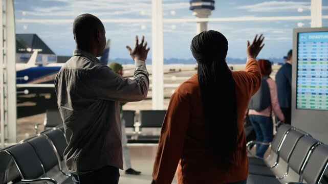 Humorous parents share high-five saying goodbye to teenager at the airport, enjoying the milestone of her independence and new journey studying abroad. Proud people with relieved expressions.