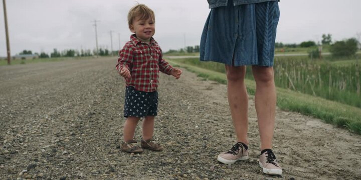 Toddler and parent standing together on a gravel road