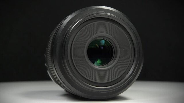 Black macro lens of Micro Four Thirds system, MFT or M43, rotates on black background