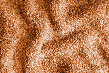 Close up, macro of crumpled orange terry towel fabric with wrinkles and soft waves. Fluffy microfiber texture with dense fibers, textile, material structure, detailed cloth abstract background © katyamaximenko
