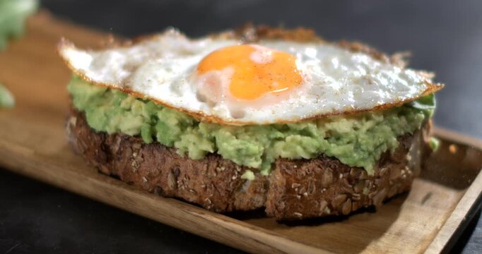 Super slow motion, Natural Light Accentuates Textured Multigrain Toast Topped With Avocado And Fried Egg