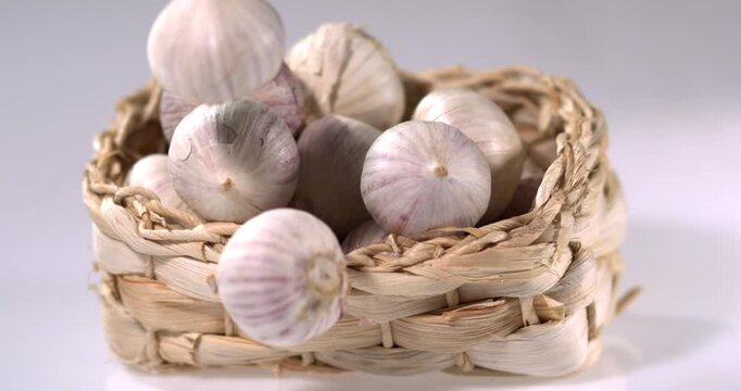 Super slow motion, Organic Garlic Stored In Braided Straw Basket With Soft Studio Lighting And Market Ambiance