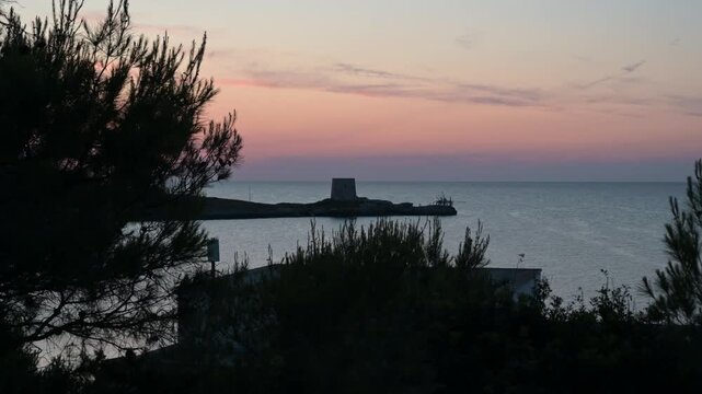 antica torre saracena vicino ad un piccolo trabucco in legno sulla costa del gargano, in puglia