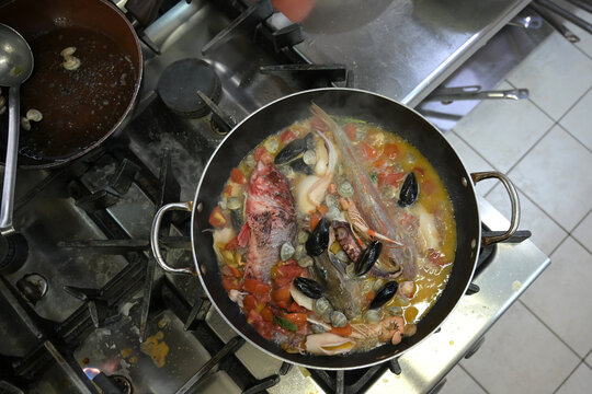 zuppa di pesce in cottura in una padella in una cucina di un ristorante
