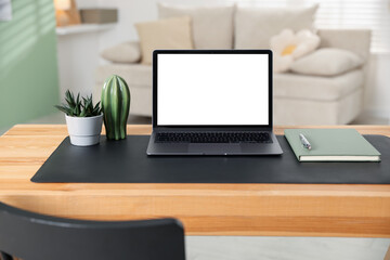 Fototapeta premium Stylish workplace with laptop, stationery and floral decor on wooden desk indoors