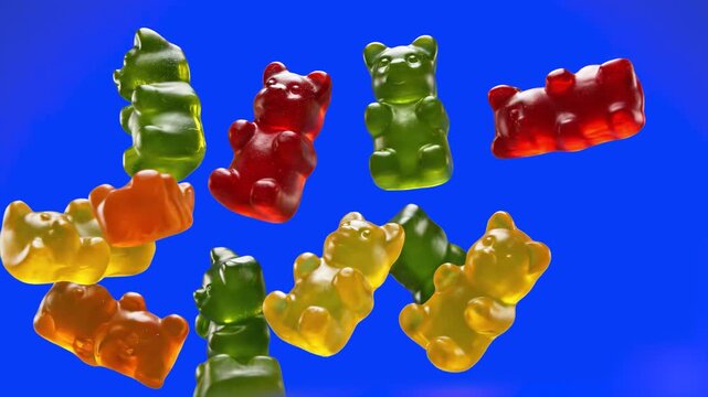 A variety of colorful gummy bears (red, green, yellow, orange) falling through the air. Set against a solid blue studio background, perfect for candy branding, snacks, or fun commercial projects.