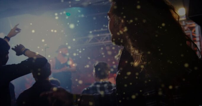 Crowd raising hands at music as vocalist singing, headbanging fan, confetti floating through crowd