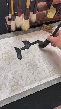 Detailed vertical view of a calligrapher creating the Chinese character for wealth or abundance on traditional paper with black ink