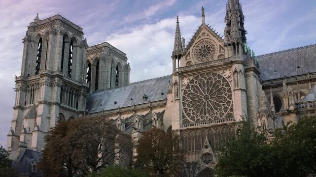 Close view of Notre Dame Cathedral with twin towers detailed rose window and gothic facade rising above trees under sky creating iconic Paris architectural scene