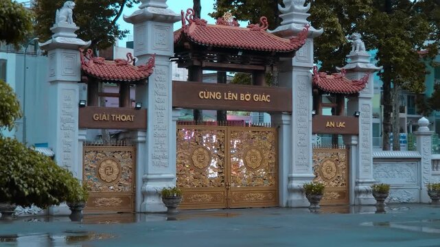 Massive majestic golden gates of Viet Nam Quoc Tu Pagoda (Vietnamese National Pagoda) carved with floral patterns and adorned with holy swastikas. Ho Chi Minh City, Vietnam