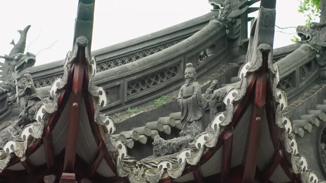 Ornate asian temple roof detail with intricate stone and wooden carvings along curved eaves, guardian figures and dragon motifs, red lacquer beams and weathered patina, closeup pan reveals symmetry,