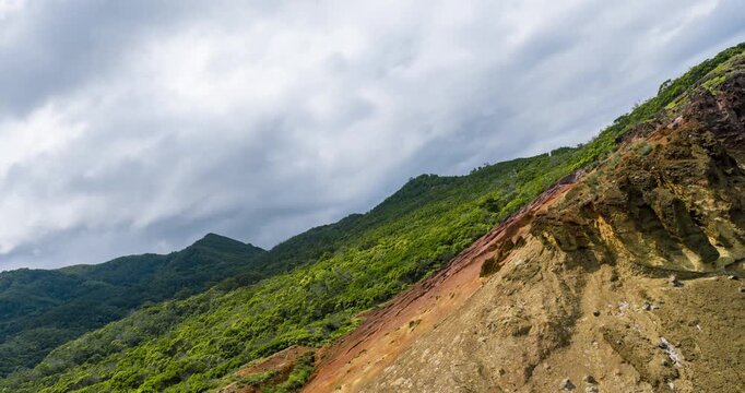 Dramatic volcanic cliff at Calhau da Furna do Bode with green slopes, rocky textures and moody clouds. aerial, hyperlapse