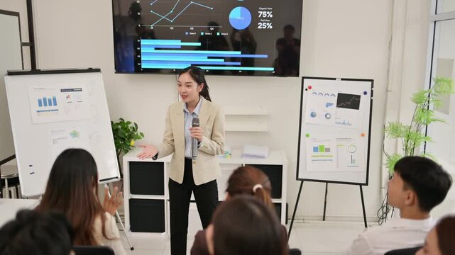 A woman is giving a presentation in front of a group of people. The presentation is about graphs and charts