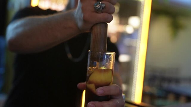 Bartender muddling fresh fruit for a cocktail